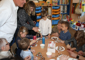 Dzieci dekorują pierniki z dziadkami i babciami.