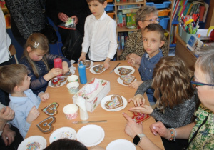 Dzieci dekorują pierniki z dziadkami i babciami.