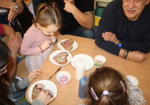 Dzieci dekorują pierniki z dziadkami i babciami.