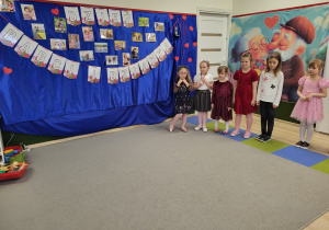 Dzieci stoją na tle dekoracji z napisem Dzień babci i dziadka.