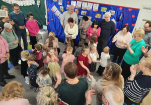 Dzieci tańczą na dywanie z babciami i dziadkami.