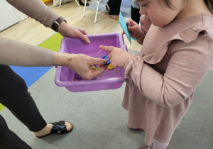 Dziewczynka bierze elementy do przyszywania guzika.