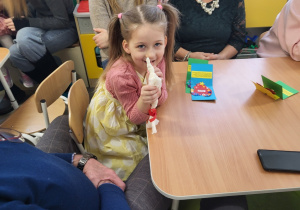 Dziewczynka pokazuje zapleciony warkoczyk z kokardką,