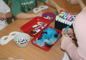 Dzieci tworzą maski karnawałowe.