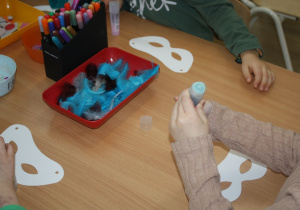 Dzieci tworzą maski karnawałowe.