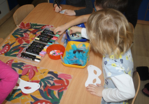 Dzieci tworzą maski karnawałowe.