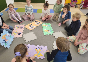 Dzieci układają obrazki Disneya z dużych puzzli.