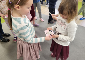 Dwie dziewczynki trzymają obrazek ze zwierzatkiem.