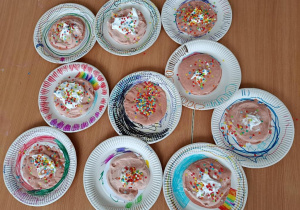 Na papierowych talerzykach projekt pączków z kolorową posypką.