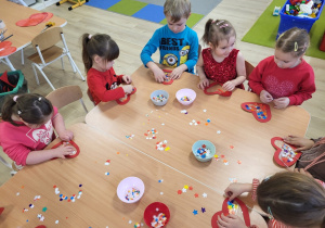 Dzieci wykonują serduszka walentynkowe.