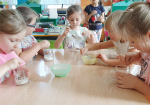 Dzieci mieszają łyżeczką desery.