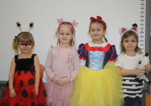 Dzieci pozują do zdjęcia w strojach karnawałowych.