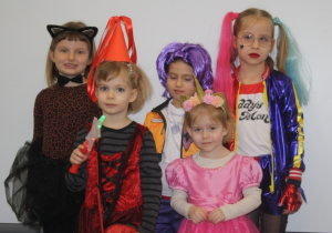 Dzieci pozują do zdjęcia w strojach karnawałowych.