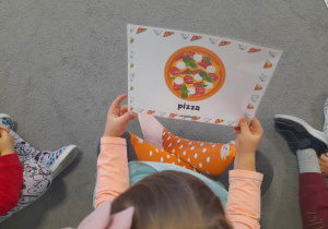 Dziecko trzyma w ręku ilustrację.