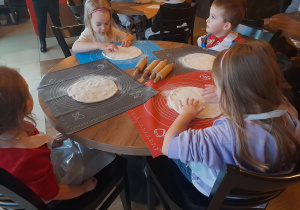 Dzieci przygotowują ciasto na pizzę.