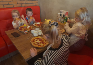 Dzieci jedzą przygotowane samodzielnie pizze.