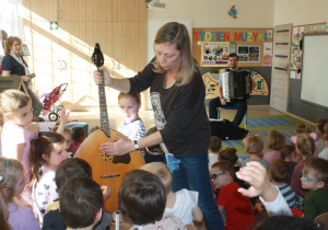 Dzieci dotykają strun w instrumencie.