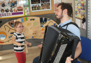 Dziecko słucha dźwięków akordeonu.