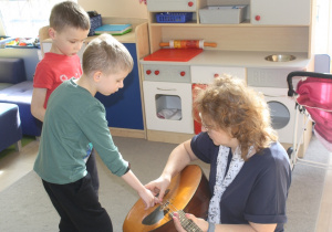 Dziecko dotyka strun w instrumencie.