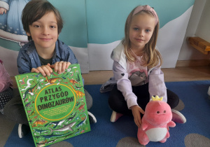 Dzieci pokazują swoją książkę i maskotkę.