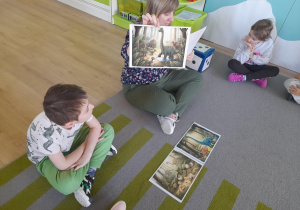 Nauczycielka pokazuje dzieciom ilustracje.