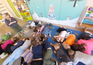 Dzieci naśladują leżące dinozaury.