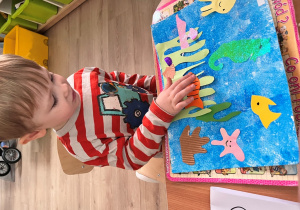 Chłopiec przykleja elementy do kartki.