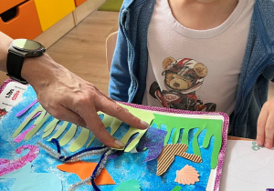 Chłopiec układa elementy rafy na kartce.