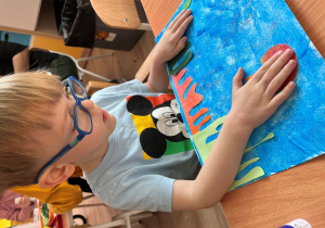 Chłopiec przykleja meduzę do kartki.