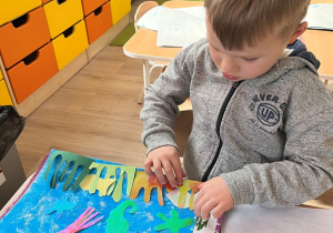 Chłopiec smaruje klejem.