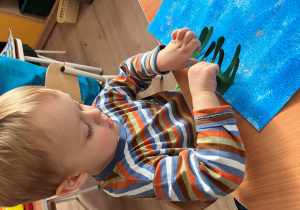 Chłopiec przykleja do kartki.