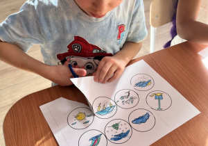 Chłopiec wycina nożyczkami.