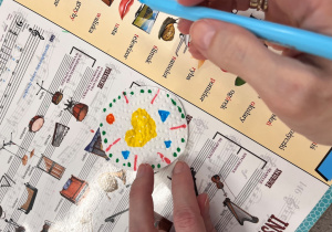 Dziecko rysuje pisakiem wzory na papierowym kółku.