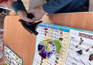 Chłopiec pryska wodą kubek z papierowymi kółeczkami.