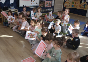 Dzieci trzymają duże karty do gry.