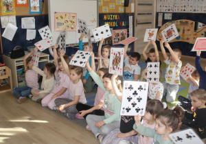 Dzieci trzymają duże karty do gry.