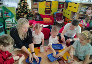 Dzieci tworzą przy stole zimowe bałwanki.