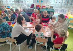 Dzieci wraz z rodzicami siedzą przy stole.