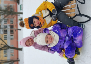 Dzieci siedzą na śniegu.