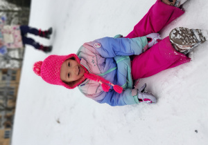 Dziewczynka siedzi na śniegu.