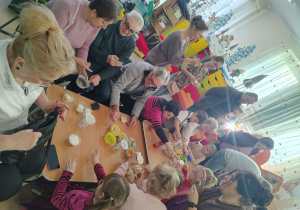 Dzieci wraz z dziadkami siedzą przy stole.