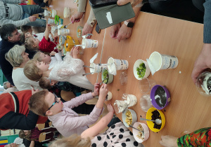 Dzieci wraz z dziadkami siedzą przy stole.