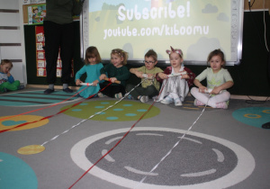 Dzieci przyciągają na wstążce monetę.