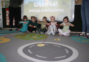 Dzieci przyciągają na wstążce monetę.