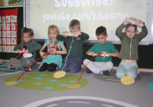 Dzieci przyciągają na wstążce monetę.