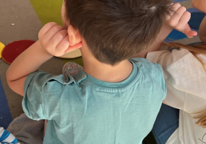 Chłopiec trzyma się za uszy.