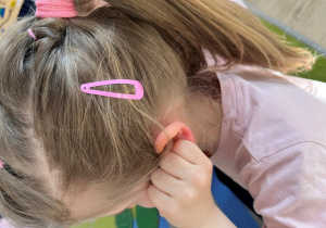 Dziewczynka trzyma się za ucho.