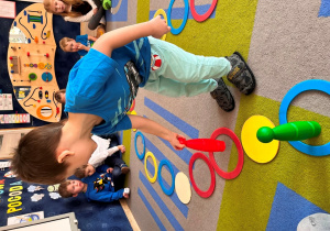 Chłopiec przestawia pionek w kolorze czerwonym.