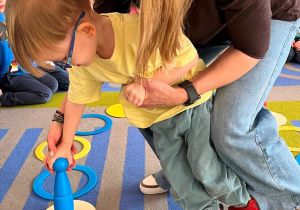 Chłopiec z pomocą nauczycielki pionek.