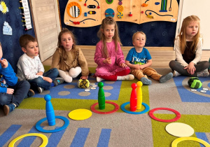 Dzieci siedzą na dywanie dookoła ułożonej gry.